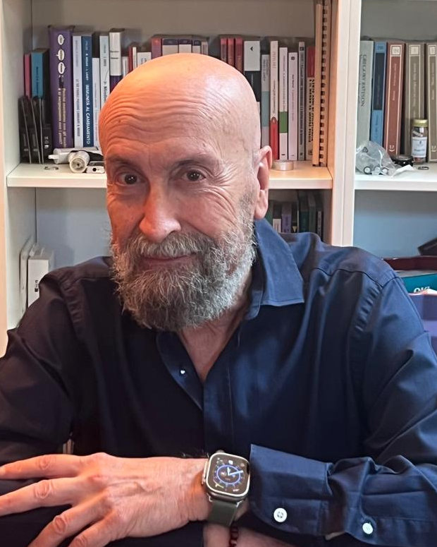 Ritratto di Camillo Sperzagni seduto alla scrivania davanti alla libreria del suo studio